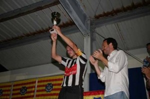 El capitán del CE Alaior levanta el trofeo de campeón ante la mirada del presidente del Consell - Javier 